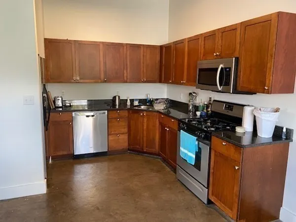 a kitchen with stainless steel appliances granite countertop wooden cabinets a stove a sink and a microwave