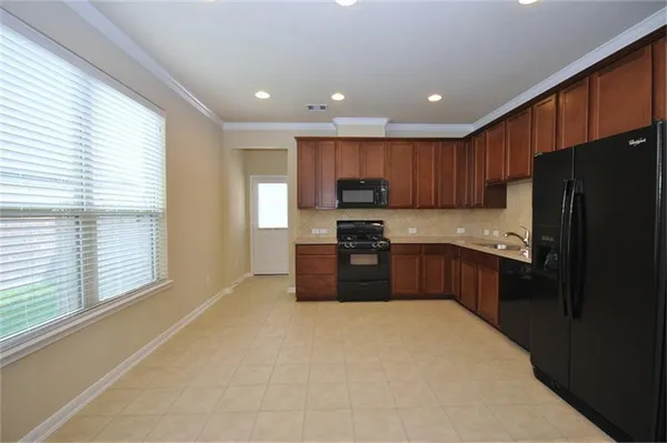a kitchen with granite countertop stainless steel appliances a refrigerator a stove top oven and a sink