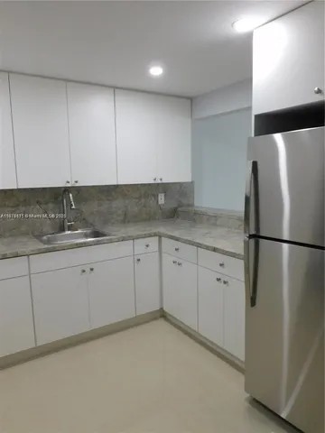 a kitchen with granite countertop cabinets and refrigerator
