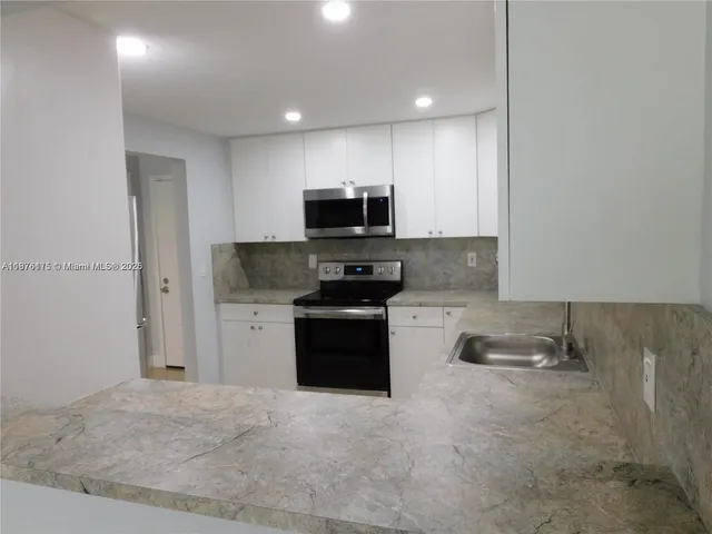a kitchen with granite countertop a refrigerator and a stove top oven