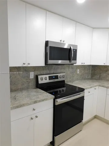 a kitchen with granite countertop white cabinets and stainless steel appliances