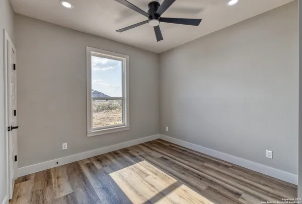 an empty room with windows and fan