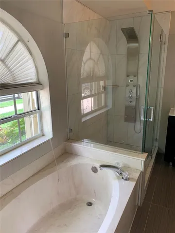 a bathroom with a tub a window and a shower