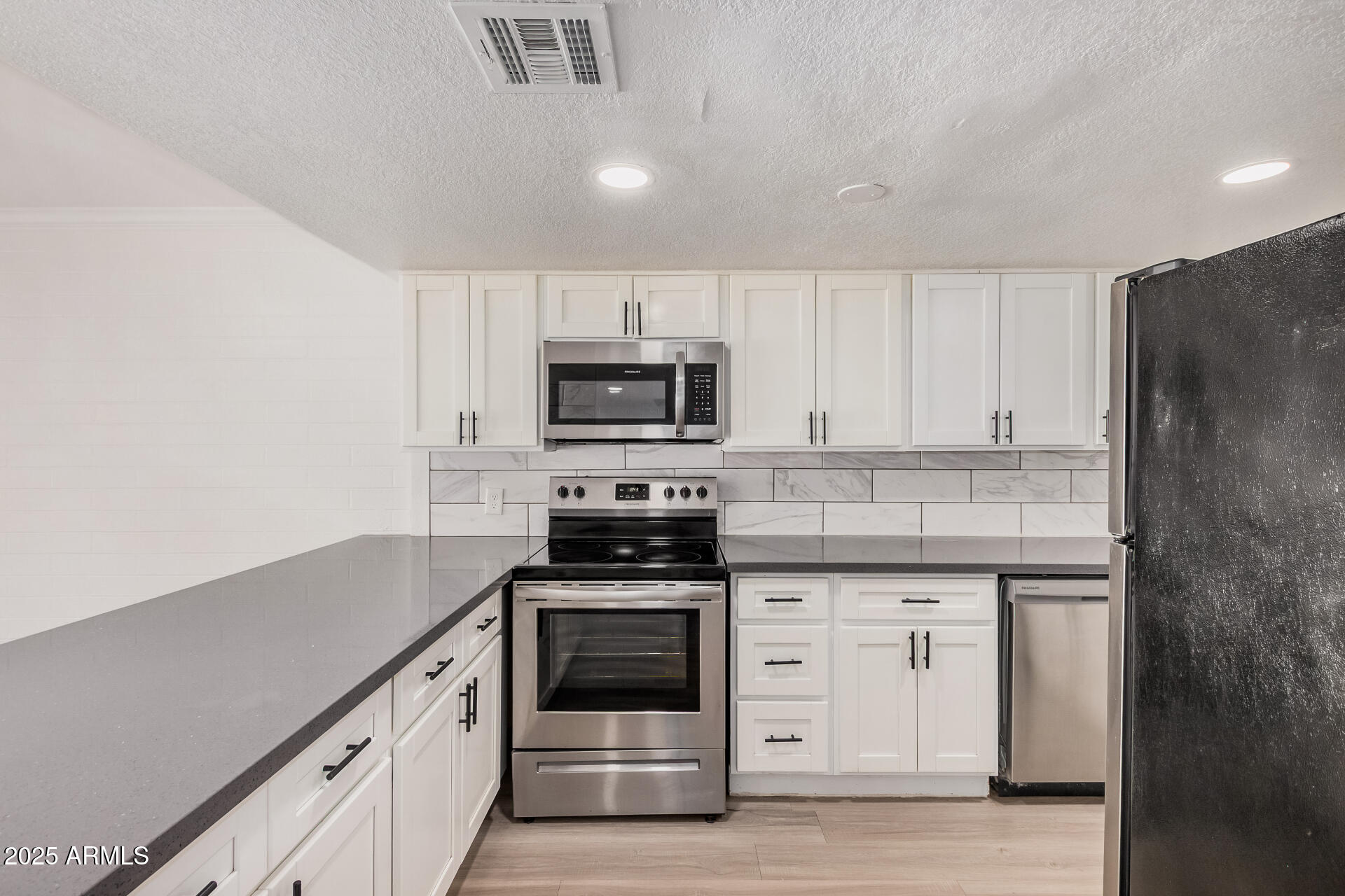 1804 West Tuckey Lane, Unit 1 Phoenix, AZ 85015 - Photo 11 of 25 a kitchen with granite countertop white cabinets and stainless steel appliances