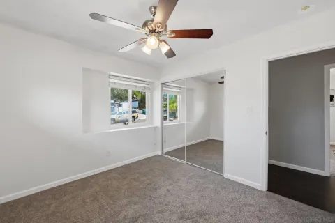 an empty room with windows and fan
