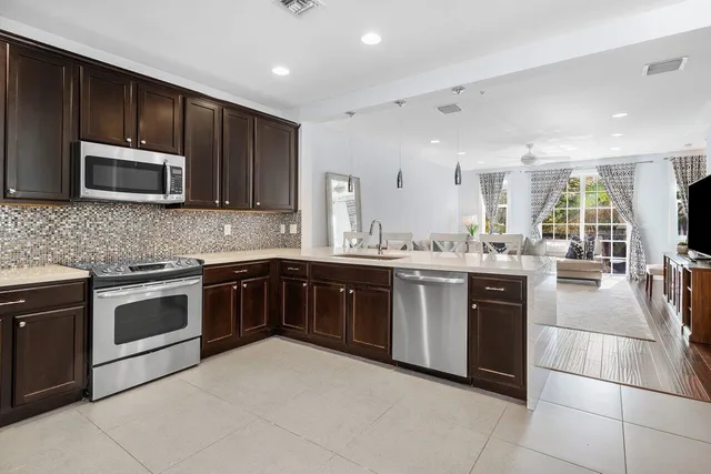 a kitchen with stainless steel appliances granite countertop wooden cabinets a stove a sink and a microwave