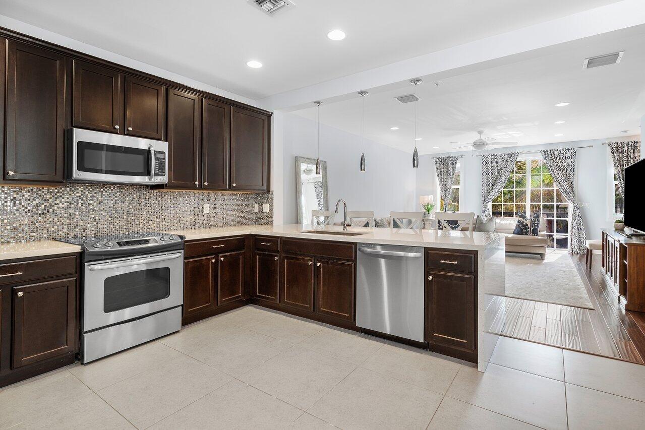 a kitchen with stainless steel appliances granite countertop wooden cabinets a stove a sink and a microwave