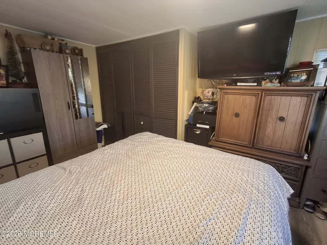a bedroom with a bed and a flat tv screen on wall