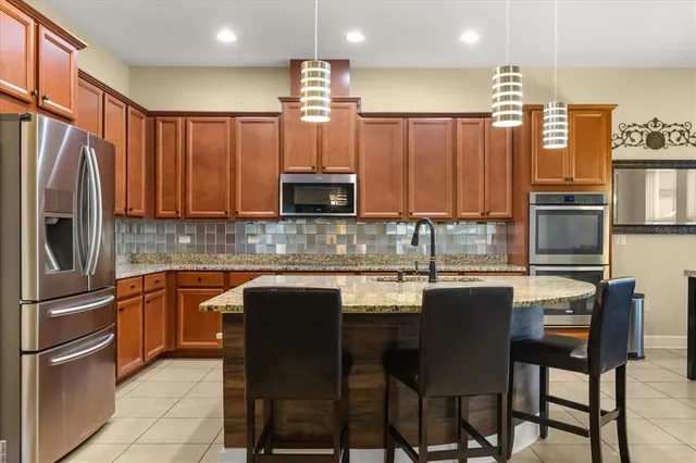 a large kitchen with kitchen island a counter top space a sink stainless steel appliances and cabinets
