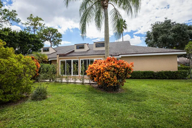 a backyard of a house with plants and large tree