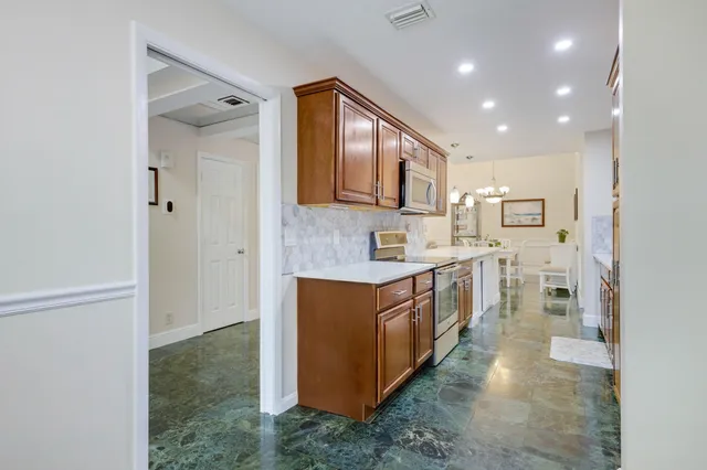 a large kitchen with stainless steel appliances granite countertop a lot of cabinets and wooden floor