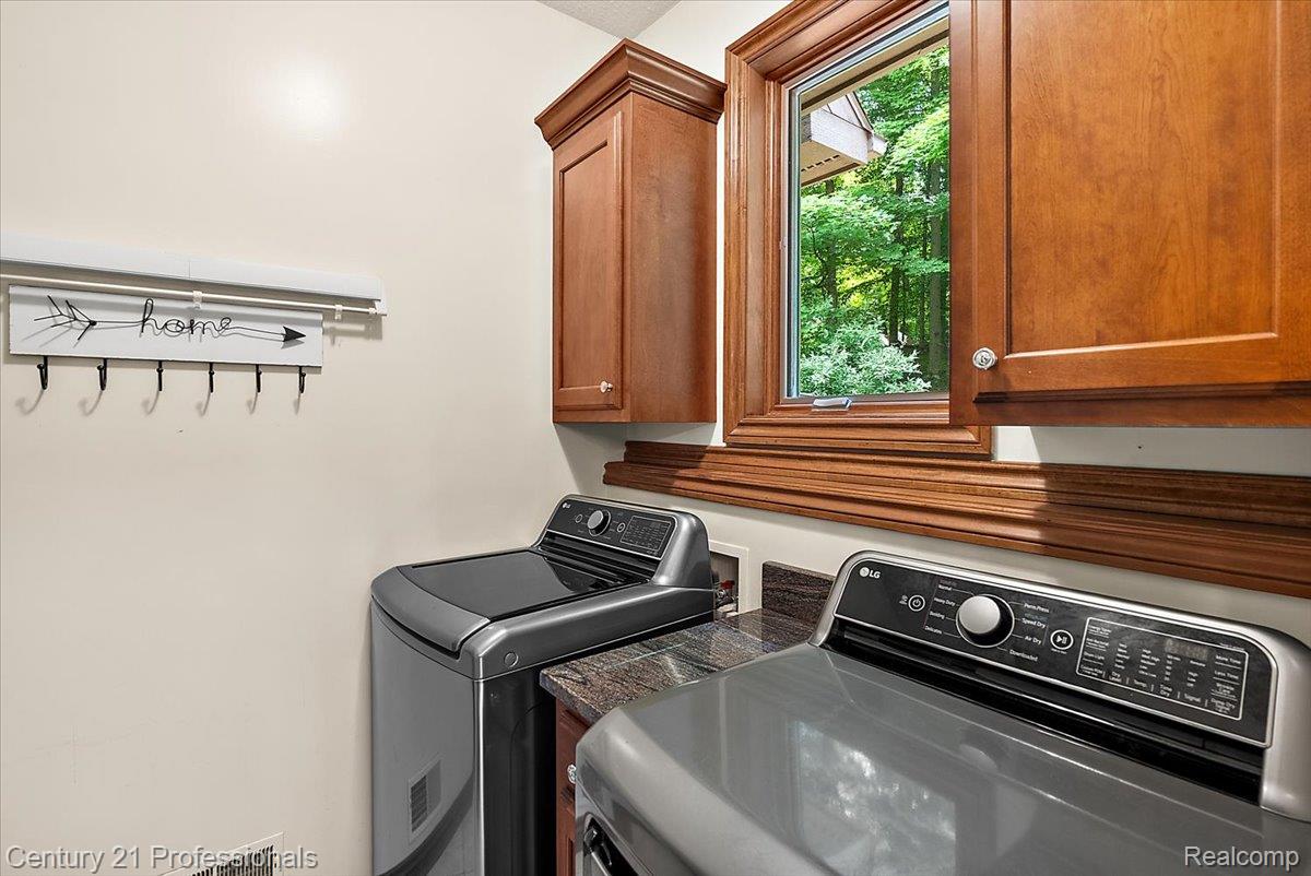 9867 Rainbow Ridge Drive Schoolcraft, MI 49087 - Photo 26 of 82 Laundry room featuring wood-finish cabinetry, granite-style countertops, and a wood-framed casement window
