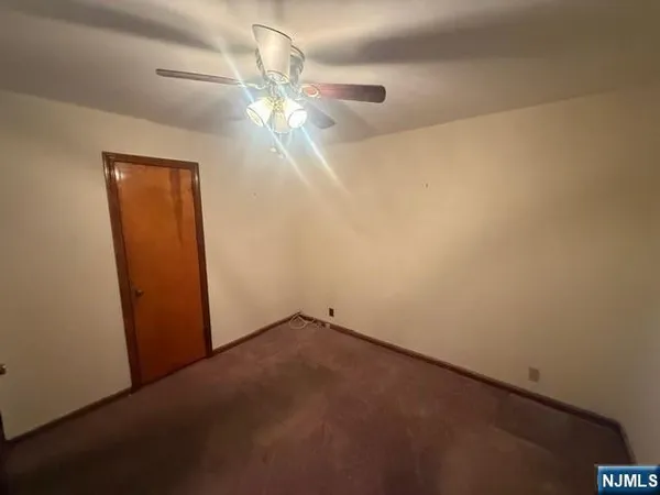 an empty room with a chandelier fan and a window