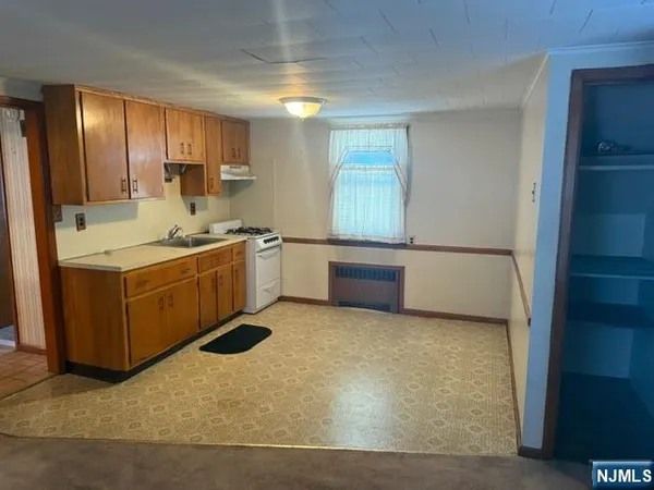 a kitchen with stainless steel appliances a sink a stove a refrigerator cabinets and a window