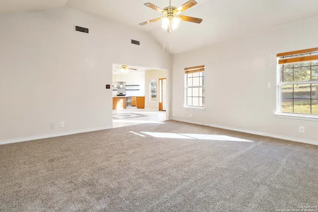 an empty room with windows and chandelier fan