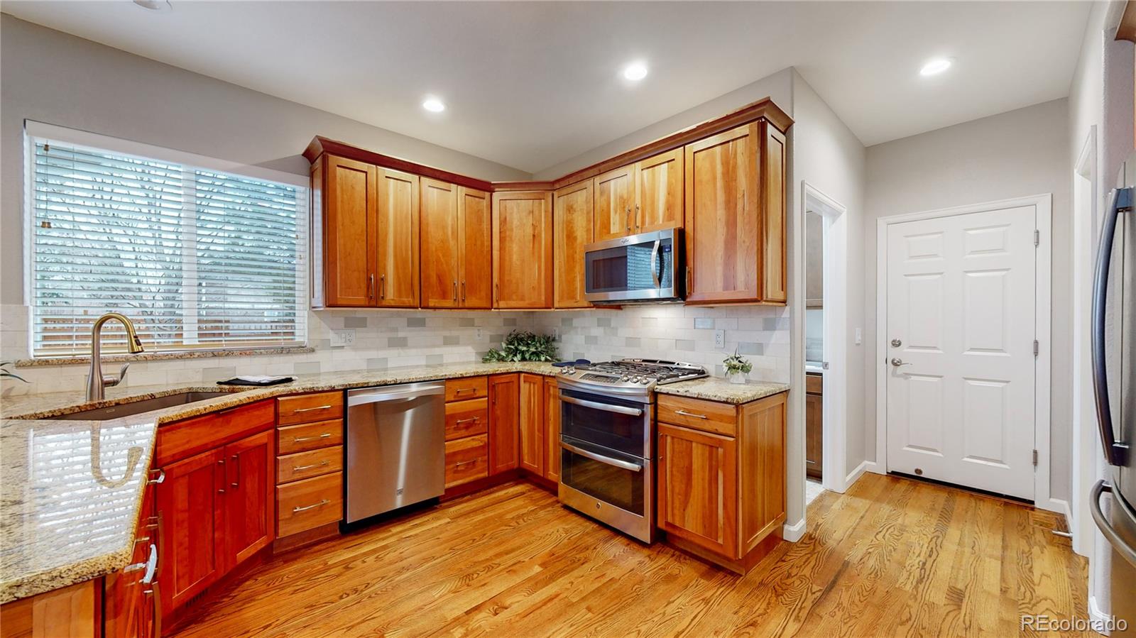 Undisclosed Address Longmont, CO 80504 - Photo 8 of 40 a kitchen with stainless steel appliances granite countertop wooden cabinets a sink dishwasher a stove and a refrigerator with wooden floor