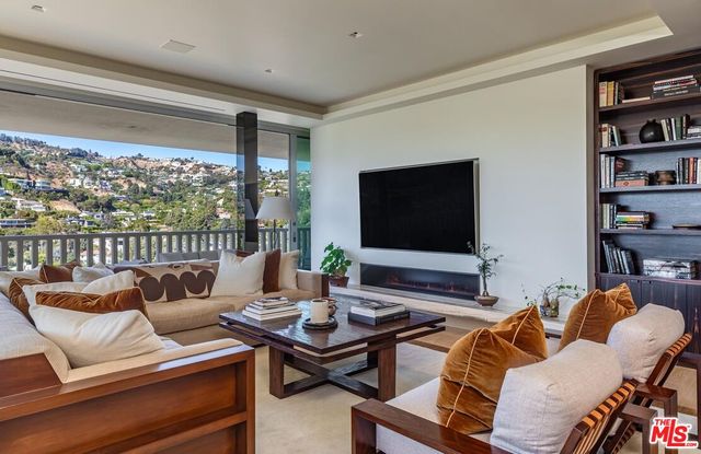 a living room with furniture a flat screen tv and a floor to ceiling window