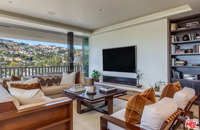 a living room with furniture a flat screen tv and a floor to ceiling window