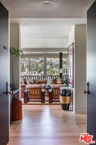a living room with stainless steel appliances furniture wooden floor and a large window