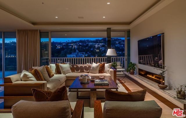 a living room with furniture a flat screen tv and a floor to ceiling window
