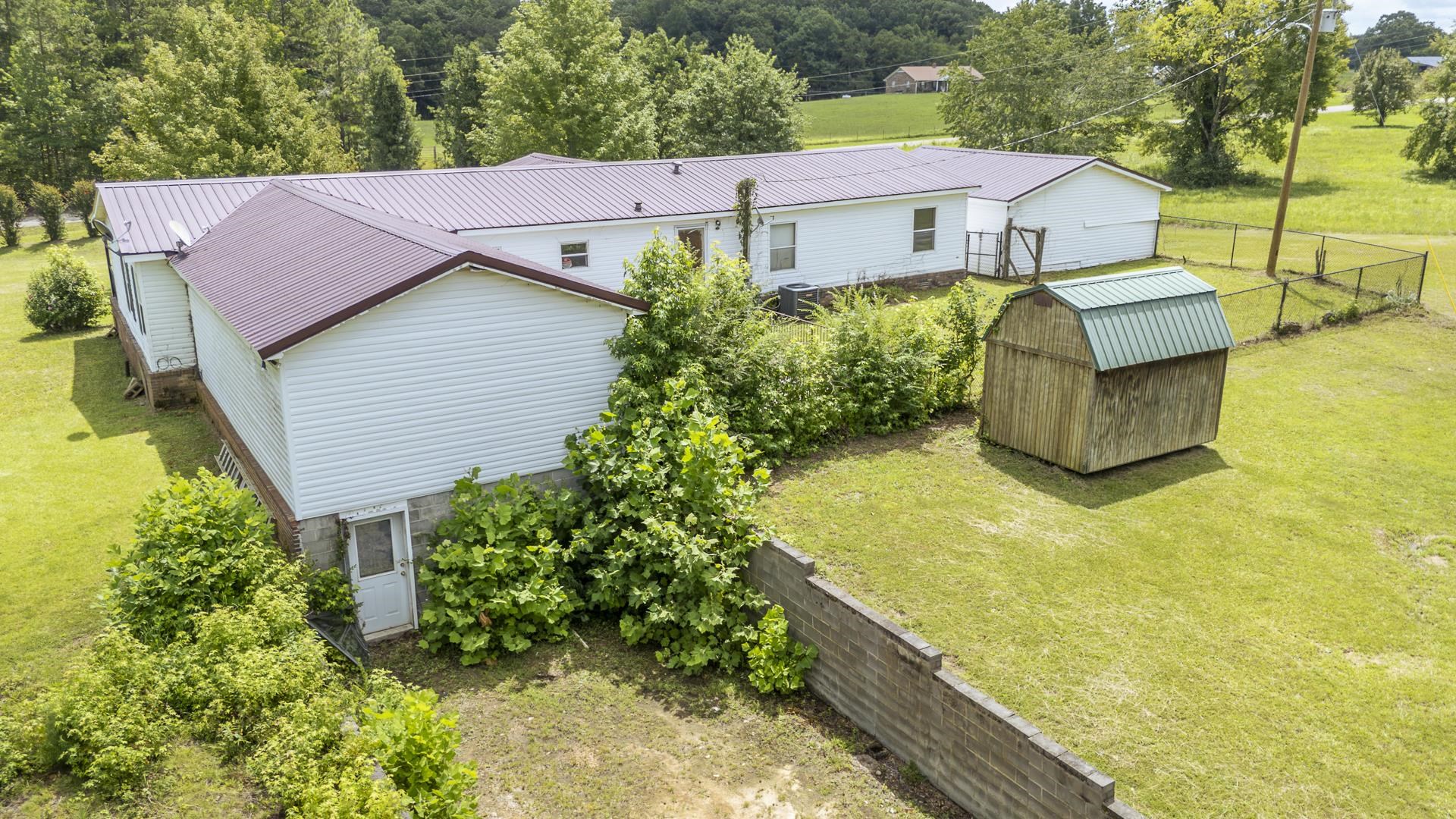 859 Old Morris Chapel Road Adamsville, TN 38310 - Photo 39 of 39 Expansive property featuring a detached storage shed with a green metal roof, a fenced yard, and a house with white siding and a brown metal roof