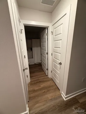 a view of a hallway with wooden floor and stairs