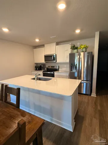 a large kitchen with stainless steel appliances a stove a sink a refrigerator and a island