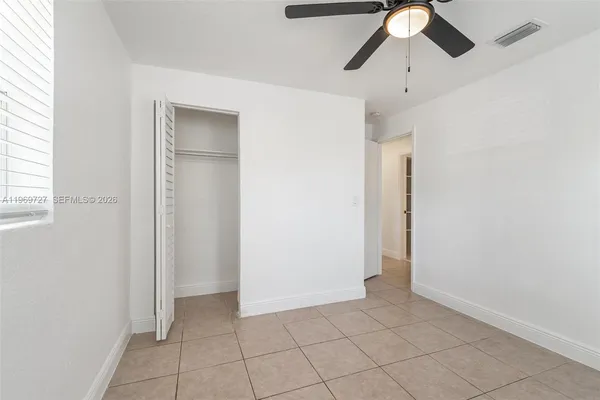 an empty room with closet and a chandelier fan