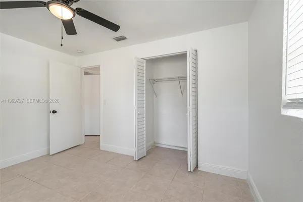 an empty room with windows and fan