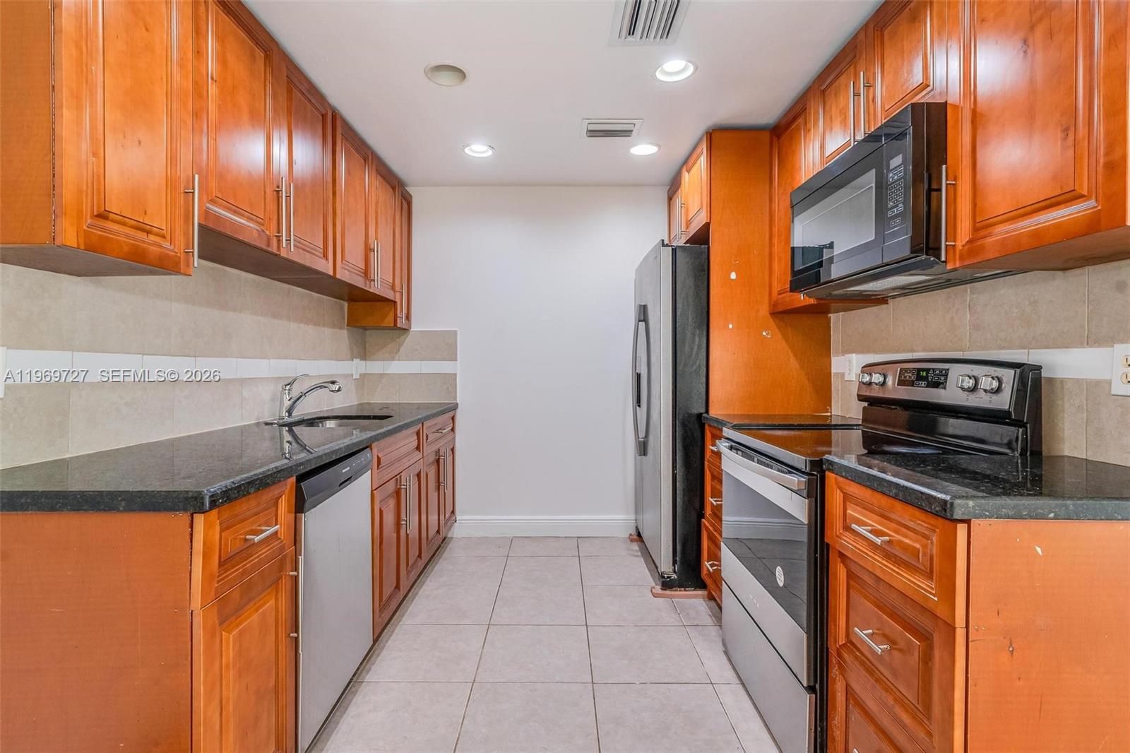 5615 Simms Street Hollywood, FL 33021 - Photo 26 of 27 a kitchen with stainless steel appliances granite countertop a stove a sink and a microwave