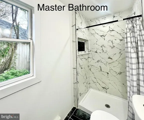 a large white kitchen with kitchen island a refrigerator a stove a sink dishwasher and white cabinets with wooden floor