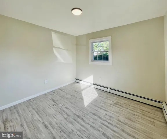 an empty room with wooden floor fireplace and windows