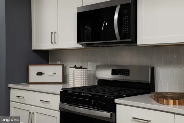 a kitchen with white cabinets and black appliances