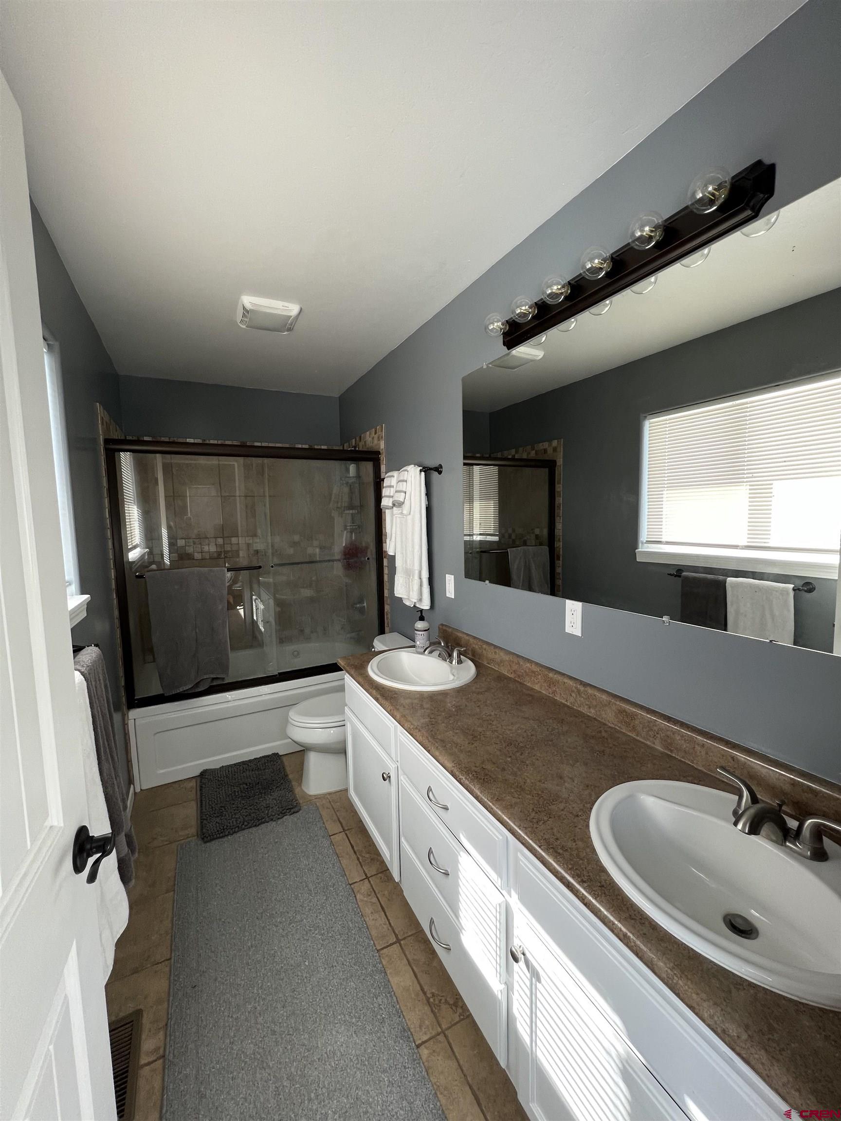 22350 Surface Creek Road Cedaredge, CO 81413 - Photo 17 of 32 a bathroom with a double vanity sink and mirror with bathtub