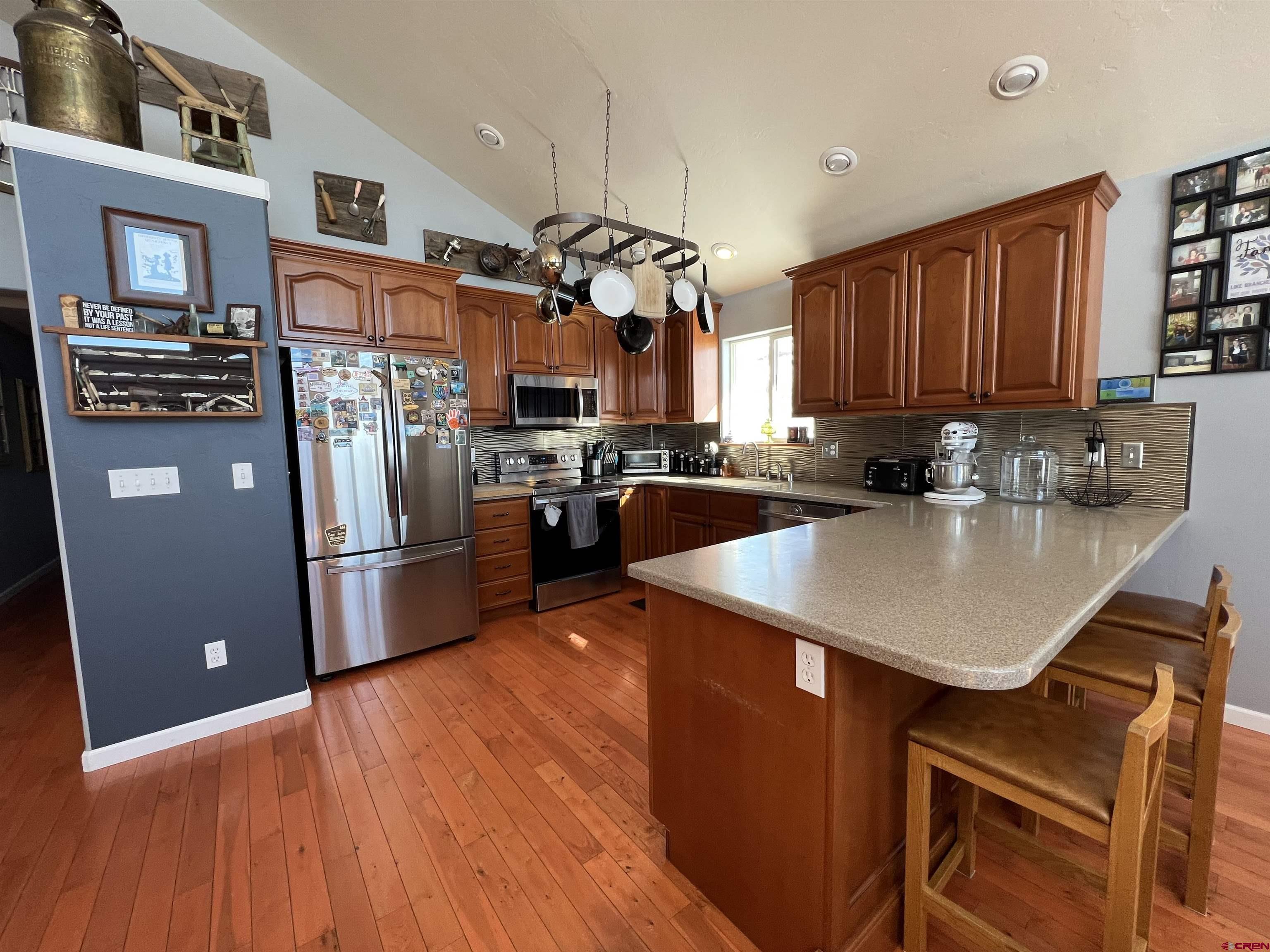 22350 Surface Creek Road Cedaredge, CO 81413 - Photo 7 of 32 a kitchen with stainless steel appliances granite countertop a refrigerator a sink dishwasher a stove a dining table and chairs with wooden floor