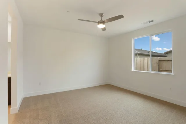 an empty room with chandelier fan and window