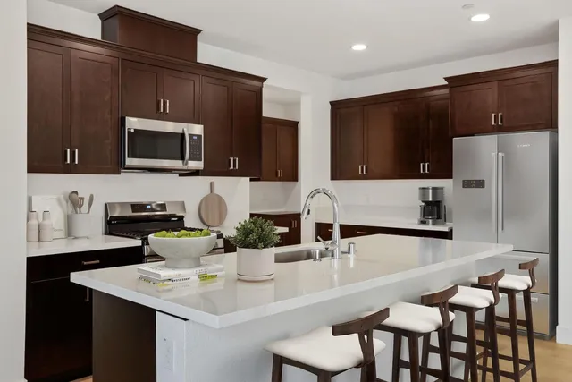 a kitchen with stainless steel appliances wooden cabinets a stove a microwave and a refrigerator