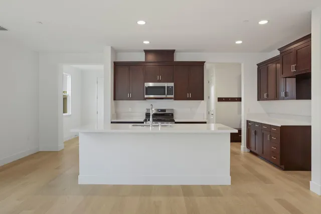 a large kitchen with stainless steel appliances a large counter top and a stove top oven