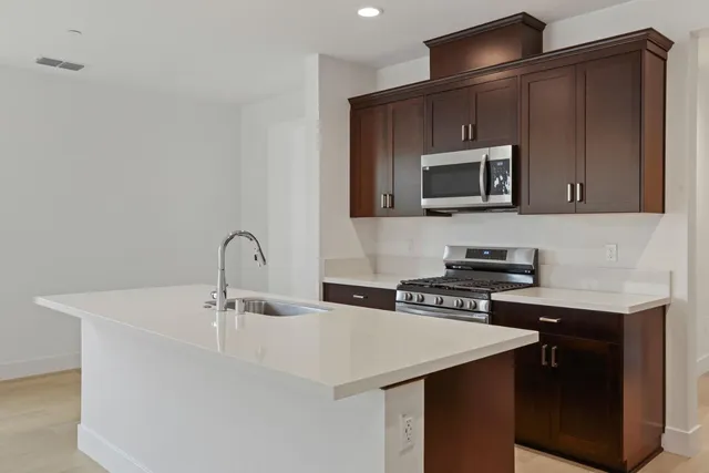 a kitchen with stainless steel appliances a stove microwave and sink
