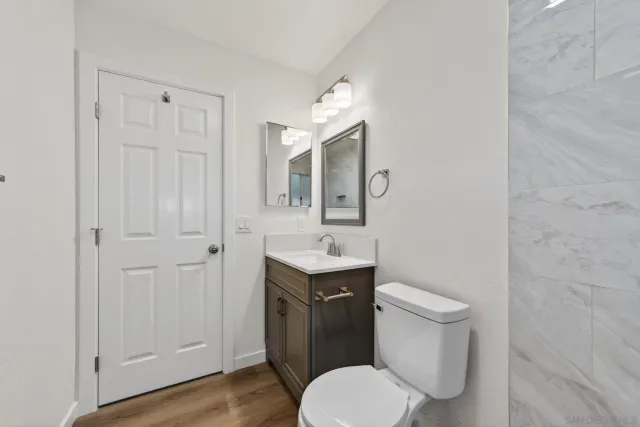 an empty room with wooden floor ceiling fan and windows