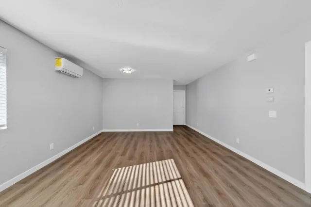 a view of an empty room with wooden floor and a window