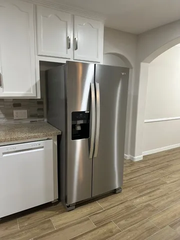 a view of a refrigerator in kitchen and an empty room