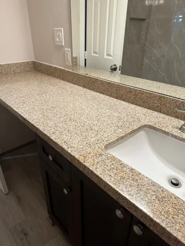 a bathroom with a granite countertop sink and a mirror