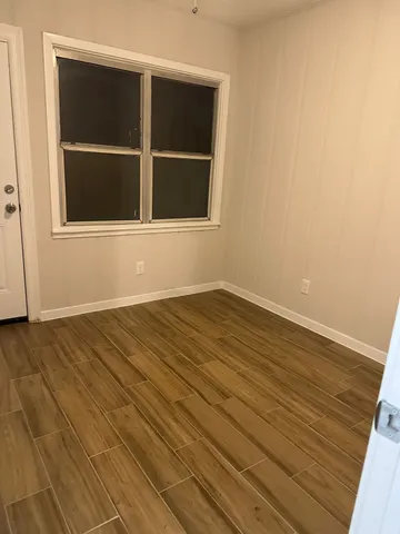 a view of empty room with wooden floor and windows