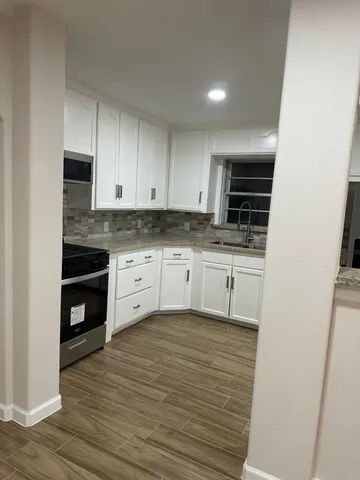 a kitchen with granite countertop a stove a sink and a microwave