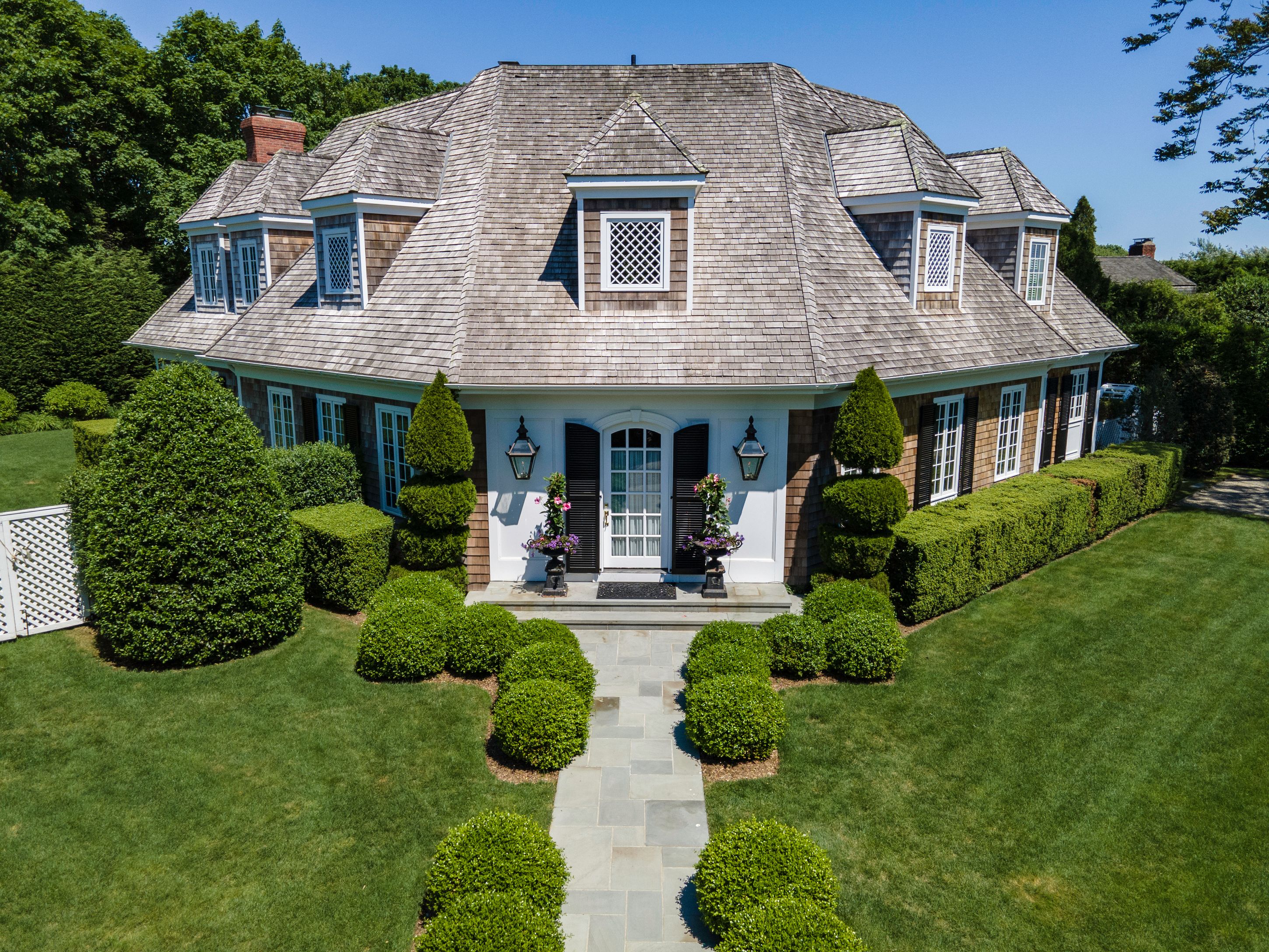 a view of a house with many windows plants and large tree