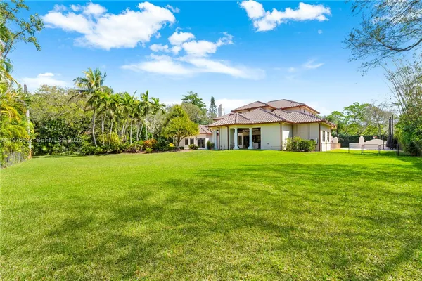 an aerial view of residential house with outdoor space and trees all around