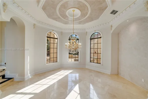 a view of an empty room with window and chandelier