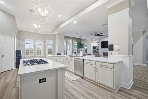 a kitchen with stainless steel appliances kitchen island granite countertop a sink and a stove top oven with wooden floor