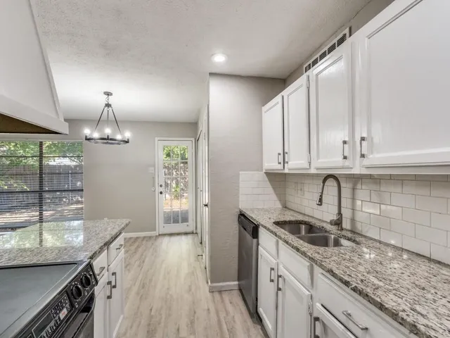 a kitchen with granite countertop a sink stainless steel appliances and cabinets
